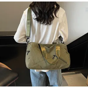 Sac de voyage vert olive porté en bandoulière pour montrer l'échelle et les dimensions