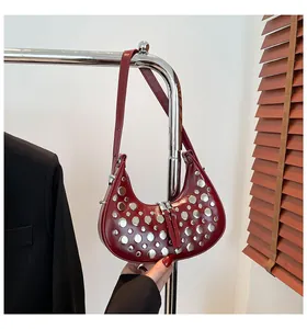 Détail de rivets argentés sur sac seau en cuir bordeaux avec fermeture éclair chic