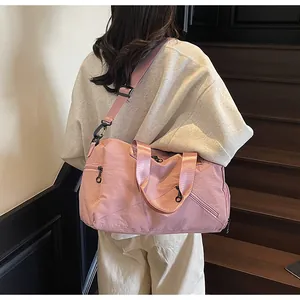 Grand sac de voyage rose imperméable porté par un mannequin dans un escalier