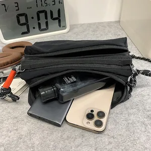 Waterproof black nylon crossbody bag with multi-layer zippers and orange charm