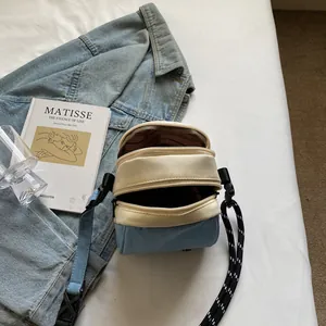 Blue denim shell crossbody bag with multi-zipper pockets and woven wide strap