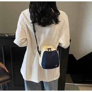 Detail of a two-tone crossbody shell bag with double zippers and blue denim patchwork