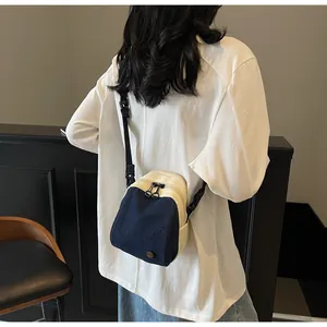 Detail view of mini shell bag showing denim and canvas stitching with double zippers