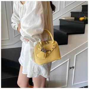 Detail of yellow shell bag with textured leather, silver zippers, and heart charm