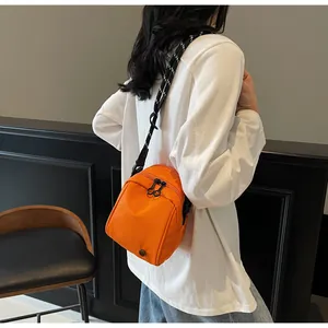 Detail view of a bright orange nylon shell bag featuring stylish patterned straps and zipper