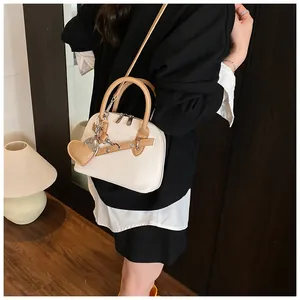 Detail of shell-shaped handbag featuring heart charm and chic two-tone contrast design
