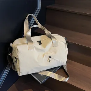 Sac de voyage et de fitness beige multifonctionnel en nylon imperméable sur un escalier en bois