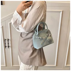 Detail of light blue pebble leather shell bag with heart charm and metal buckle strap