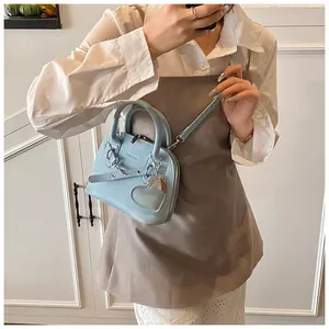 Detail of light blue shell bag with lychee grain leather, heart charm, and strap