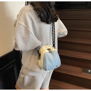 Detailed view of the denim patchwork shell crossbody bag worn by a model on stairs