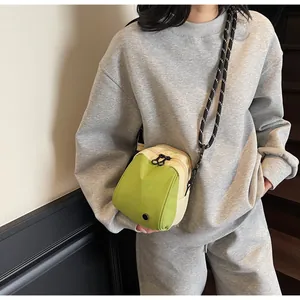 Detail of green and beige shell bag with striped woven rope strap and metal eyelet