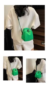 Detail view of bright green multi-zipper mini shell bag with adjustable strap