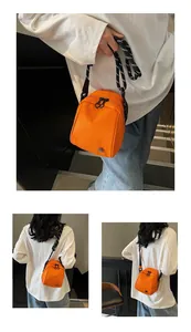 Detail view of bright orange shell crossbody bag with adjustable textured shoulder strap