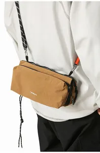 Detail of khaki nylon crossbody bag with woven shoulder strap and logo text