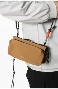 Close-up of earth brown nylon crossbody bag with white logo and orange rope detail
