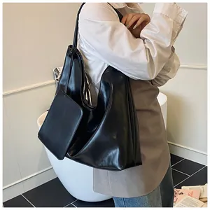 Dettaglio di una grande borsa hobo in pelle nera con una piccola pochette su una modella