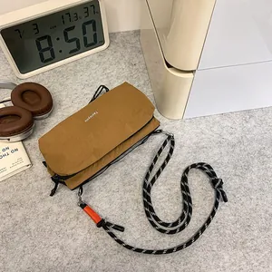 Brown textured nylon crossbody bag with dual zippers and woven cord strap for outdoor use