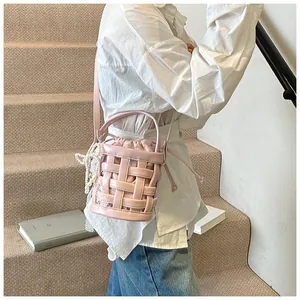 Dettaglio borsa a secchiello intrecciata rosa con catena di perle e pizzo su modella