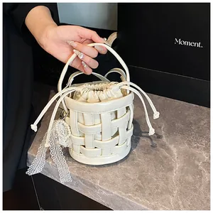 Dettaglio borsa a secchiello intrecciata crema con ciondolo in pizzo e perle decorative