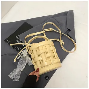 Dettaglio della borsa a secchiello intrecciata beige con fodera e ciondolo di perle