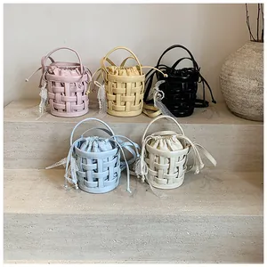 Dettaglio di mini borse a secchiello intrecciate in rosa, giallo, nero, blu e bianco crema