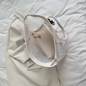 Minimalist clear PVC tote bag set with cream inner pouch on a white background