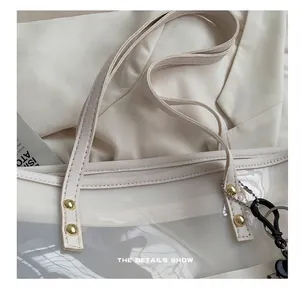 Detail van de witte transparante PVC-draagtas met PU-handvatten en gouden klinknagels