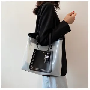 Detail of transparent PVC tote bag featuring black leather trim and cute bear charm