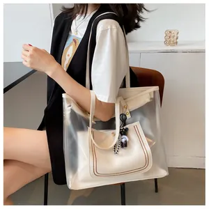 Detail view of large transparent tote bag with cream leather inner pouch and bear charm