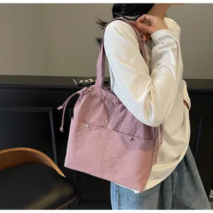 Detail of dusty pink nylon tote bag with drawstring closure and front pockets for women