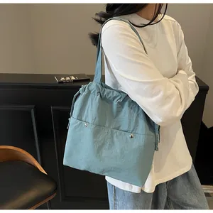 Detail of grey-blue nylon tote bag with multi-pockets, drawstrings, and silver rivets