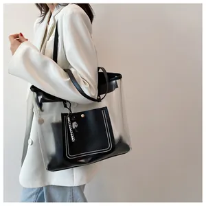 Detailed shot of a clear PVC tote with black leather trim and a checkered bear charm