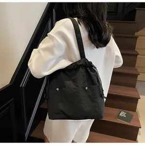 Detail of a large black waterproof nylon tote bag with drawstring and silver buckle