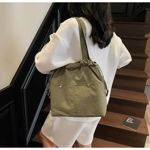 Model wearing army green nylon drawstring tote bag on a wooden staircase background