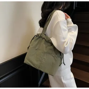 Close-up of grass green nylon tote bag featuring drawstring detail and silver metal rivets