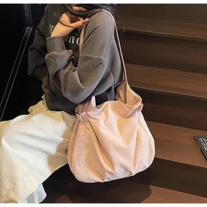 Detail of pink nylon tote bag showing soft texture and side silver buckle on a shoulder bag