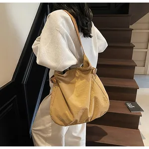 Close-up of light brown nylon tote bag showing side metal buckle and shoulder strap detail