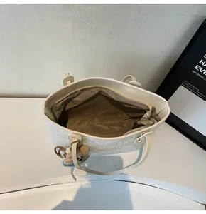 Vista dall'alto della borsa tote in pizzo crema con interno capiente e ciondolo a orsetto
