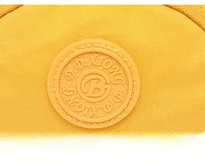 Detail einer hellgelben wasserfesten Nylontasche mit einem runden D.D.XIONG Silikon-Logo