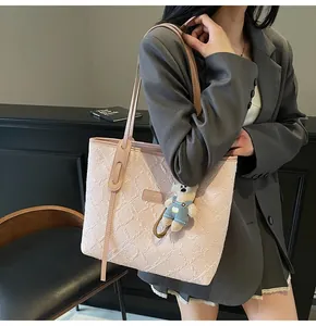 Dettaglio della borsa tote rosa chiaro con trama floreale a rilievo e ciondolo a orsetto
