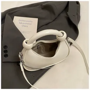 Minimalist beige leather half-moon handbag with knotted handle and detachable shoulder strap