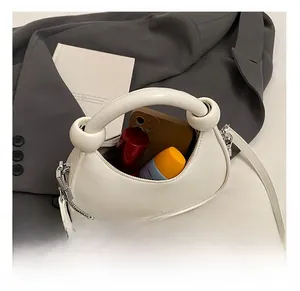Interior view of mini white dumpling bag showing space for phone and makeup items