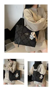 Dettaglio della borsa tote nera testurizzata con paillettes e charm a forma di orsetto