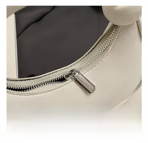 Macro shot of silver metal zipper and smooth cream leather texture on the mini handbag