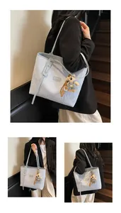 Dettaglio della borsa tote in jacquard celeste con logo in pelle e ciondolo a orsetto
