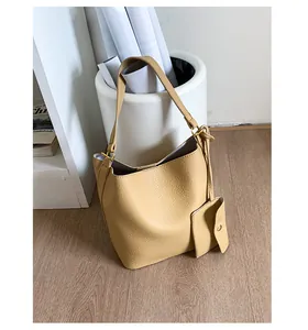 Gros plan du sac seau en cuir jaune clair à motif litchi avec boucle en métal réglable