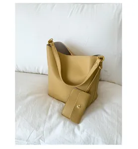 Détail du sac seau jaune en cuir grainé avec une petite pochette à bouton-pression doré