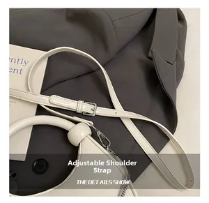 Detail of minimalist cream dumplings bag featuring a smooth faux leather adjustable shoulder strap