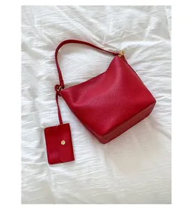 Détail du sac seau en cuir grainé rouge avec une petite pochette suspendue assortie