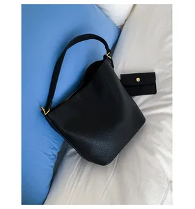 Détail du sac seau en cuir noir grainé avec ferrures dorées et petite pochette assortie